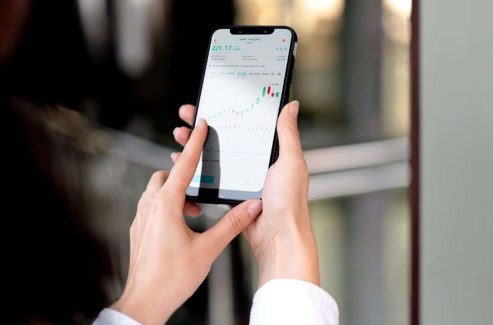 woman’s hands holding a smartphone with an open finance app on the screen