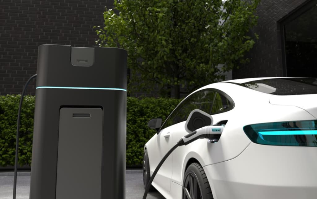 An electric car being charged at a modern charging station with green foliage in the background