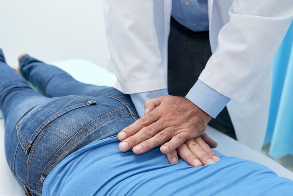 Osteopath adjusting back of patient with massage