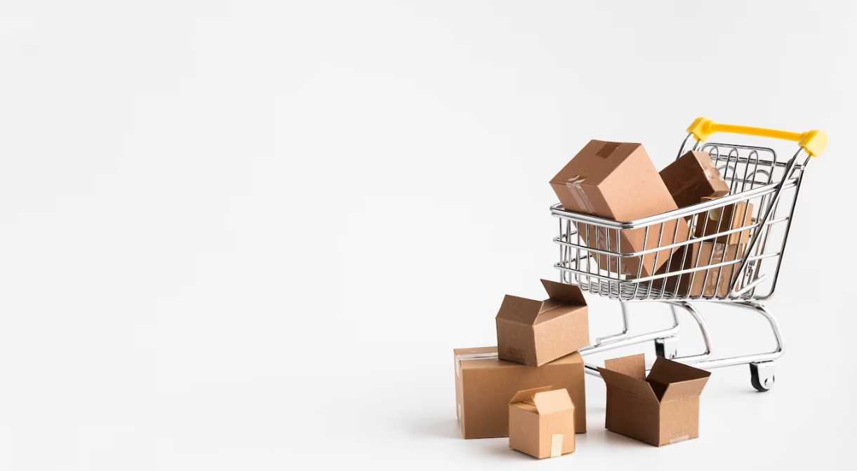 A small shopping cart tipped over with several cardboard boxes spilled out onto a white surface
