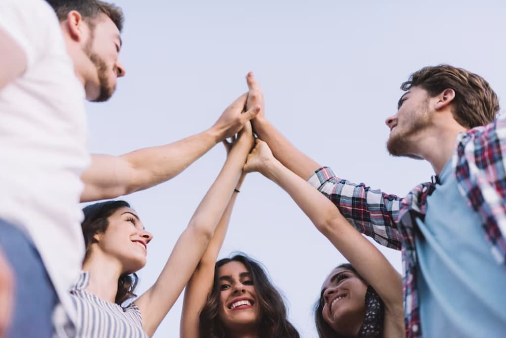 A group of friends high-fiving in a joyful, casual outdoor setting